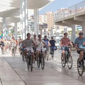 Landausfluggäste fahren entlang der modernen Hafenpromenade Málagas