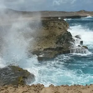 Wellen peitschen an die raue Küste von Aruba