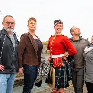 Vier Touristen posieren mit einem Darsteller in traditioneller Uniform in Citadel Hill